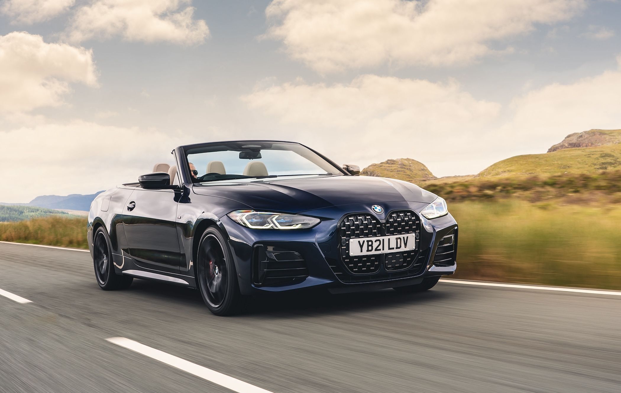 Dark blue BMW 4 Series Convertible driving along road