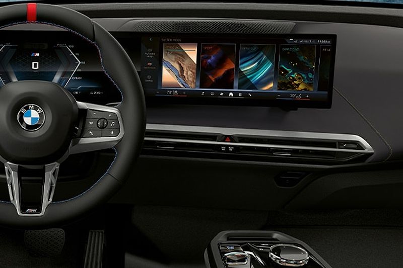 Detail of steering wheel and BMW Curved Display with colorful drive mode selections.